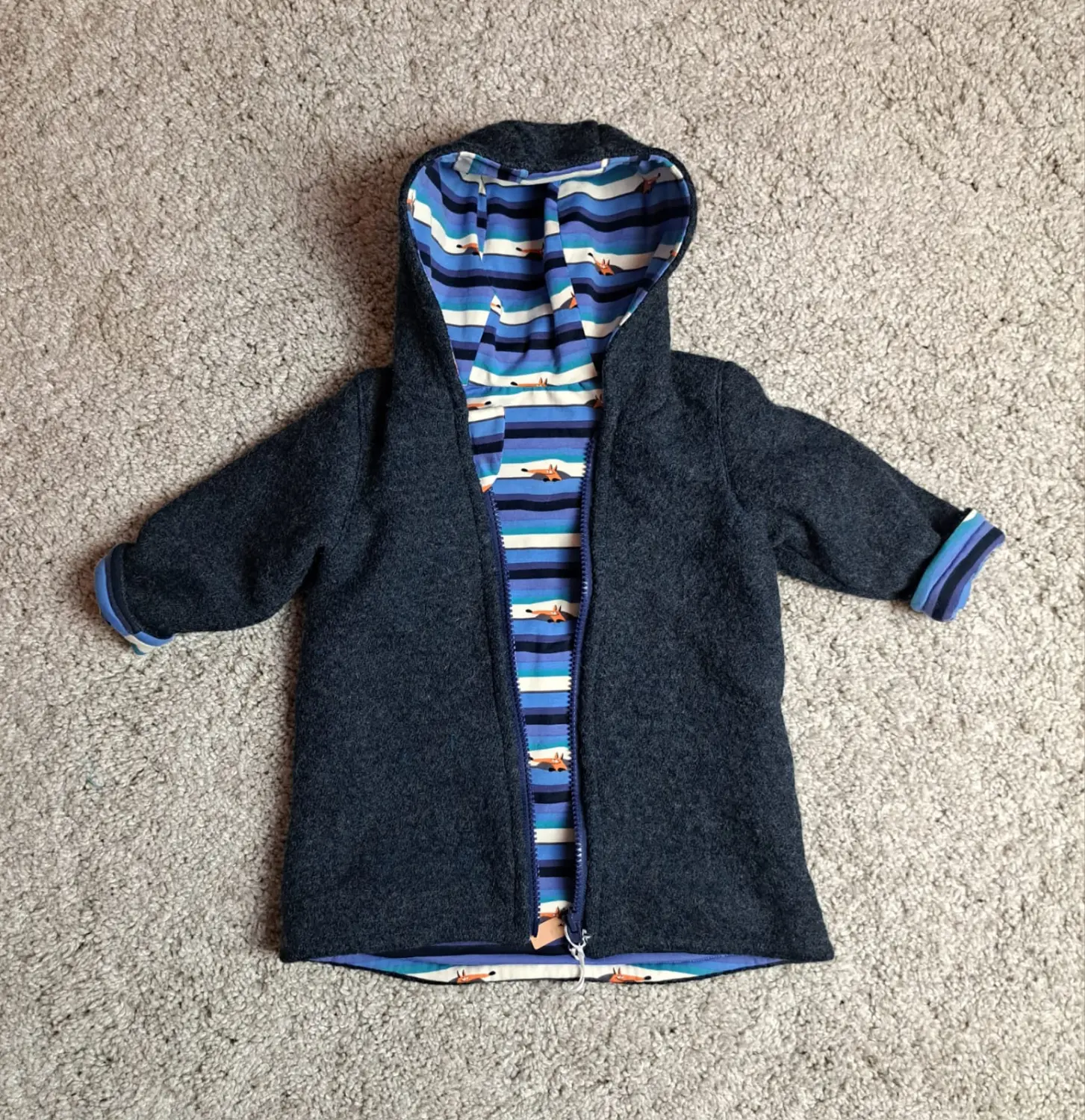 Walkjacke in Dunkelgrau mit Kapuze, blau gestreiftem Innenfutter und blauen Bündchen